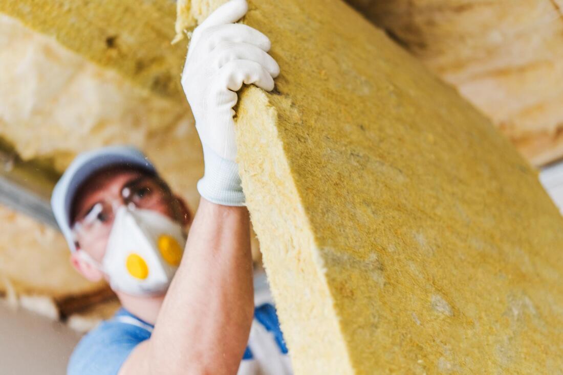 a man installing firberglass insulation